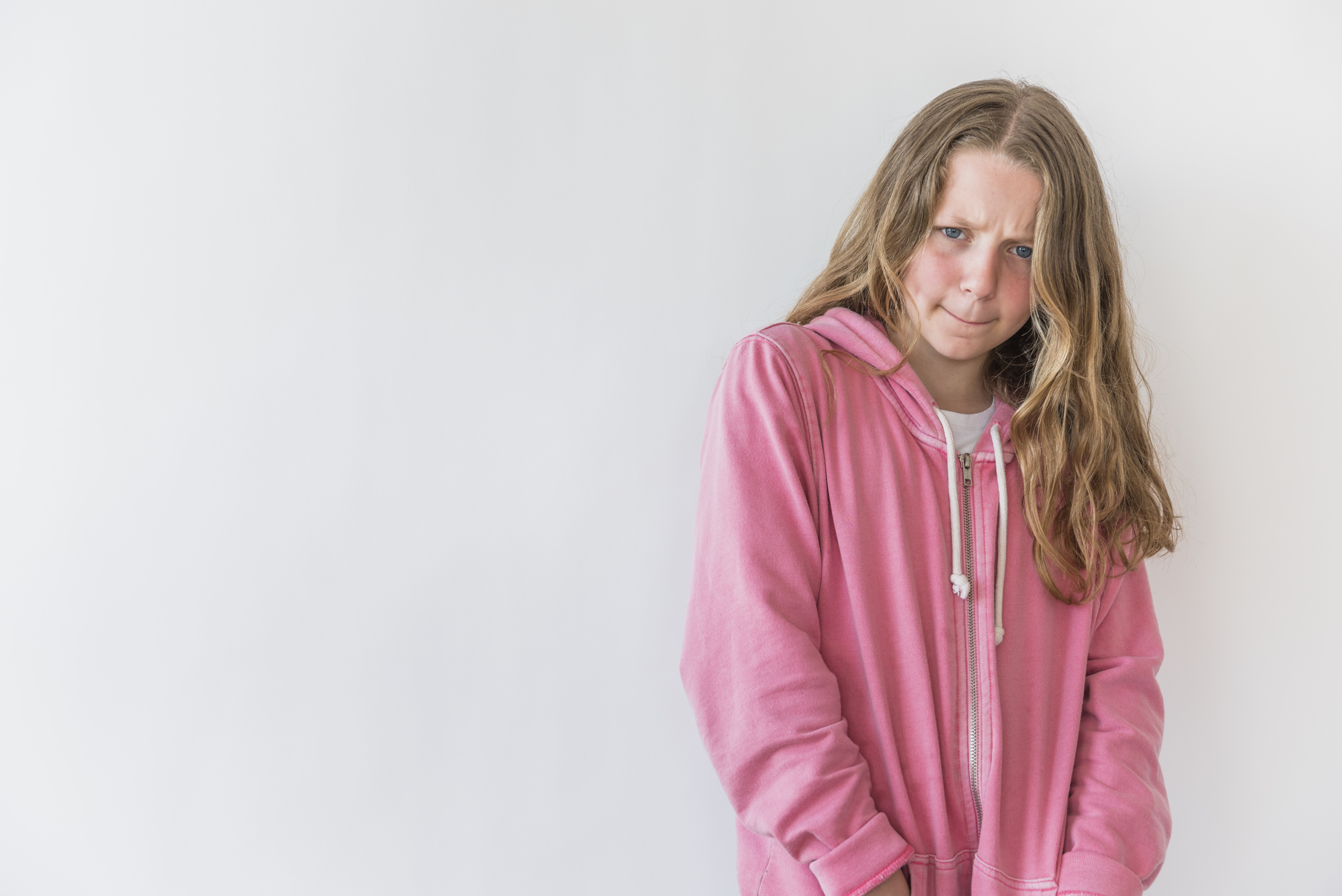 Niña con expresión preocupada vistiendo sudadera rosa, imagen representativa de pubertad precoz en Madrid Centro